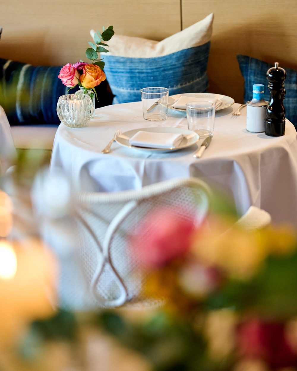 Une table dressée pour deux avec des roses et des coussins