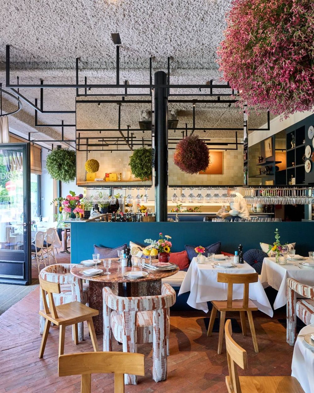 La salle avec le bar, des boules de fleurs au plafond et des assiettes au mur
